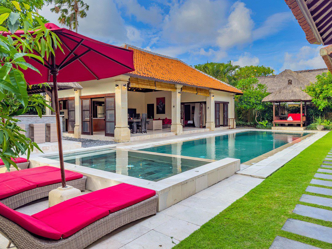 Tropical oasis landscape and spacious poolside relaxation area at Villa Santi Seminyak by Villa Bugis, ideal for family vacations in a villa Seminyak.