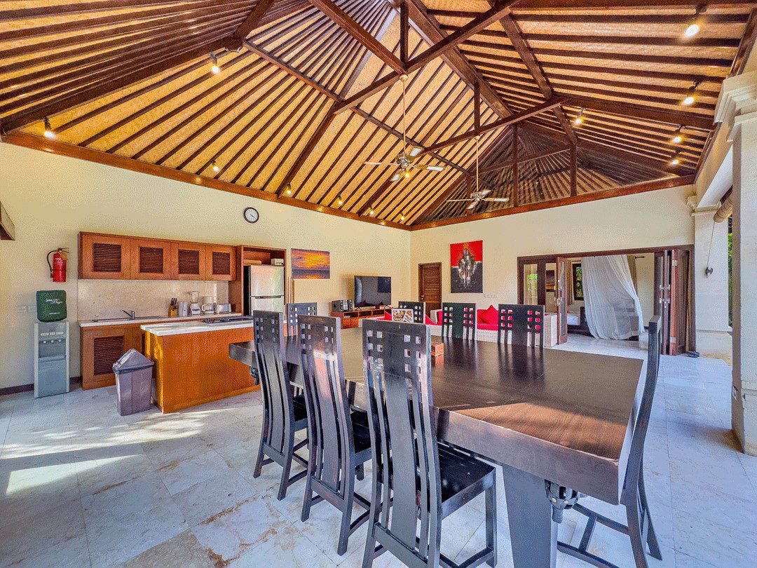 Tropical indoor-outdoor living and dining space overlooking the pool and garden at Villa Santi Seminyak by Villa Bugis Seminyak villas.