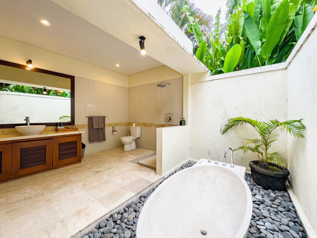 Clean modern vanity, stone basin, and a soaking bathtub in the master bathroom at Villa Santi Seminyak by Villa Bugis Seminyak villas.