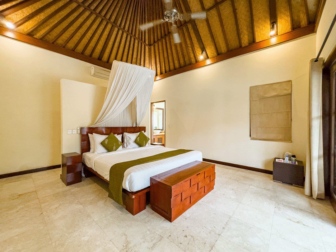 Spacious interior layout of bedroom 1 at Villa Santi Seminyak by Villa Bugis Seminyak villas, complete with air conditioning and elegant wooden furnishings.