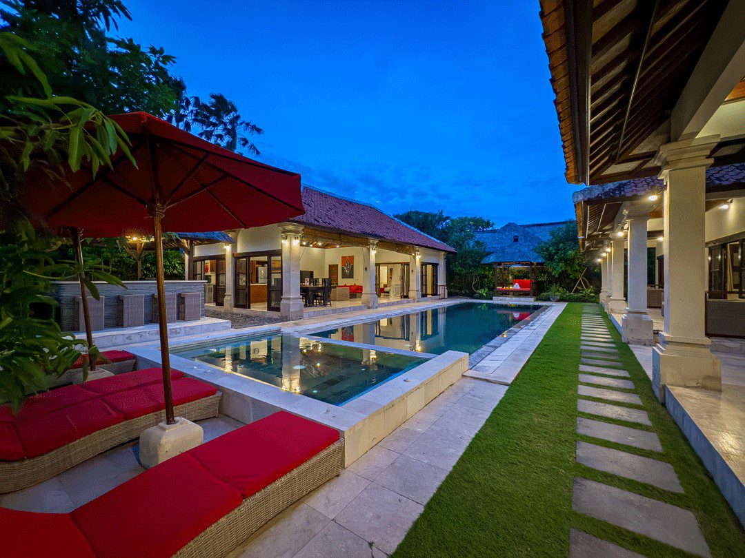 Serene evening ambiance with warm pool lighting reflecting on the water at Villa Santi Seminyak by Villa Bugis Seminyak villas.