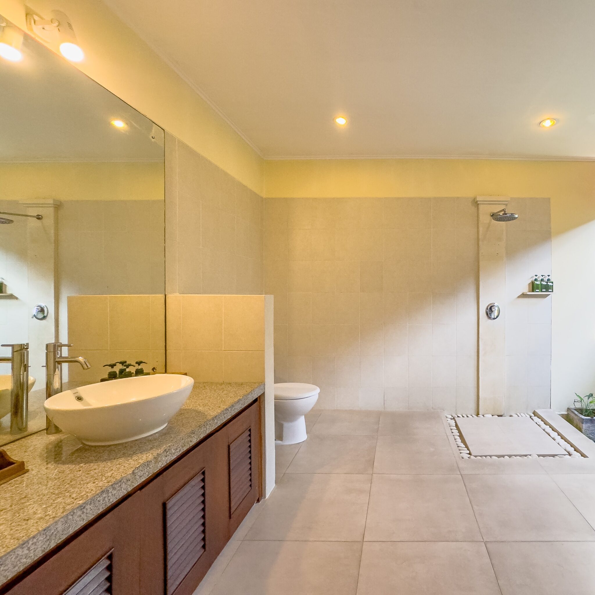 Clean modern vanity, stone basin, and refreshing shower area in the master bathroom at Villa Saphir Seminyak by Villa Bugis Seminyak villas.