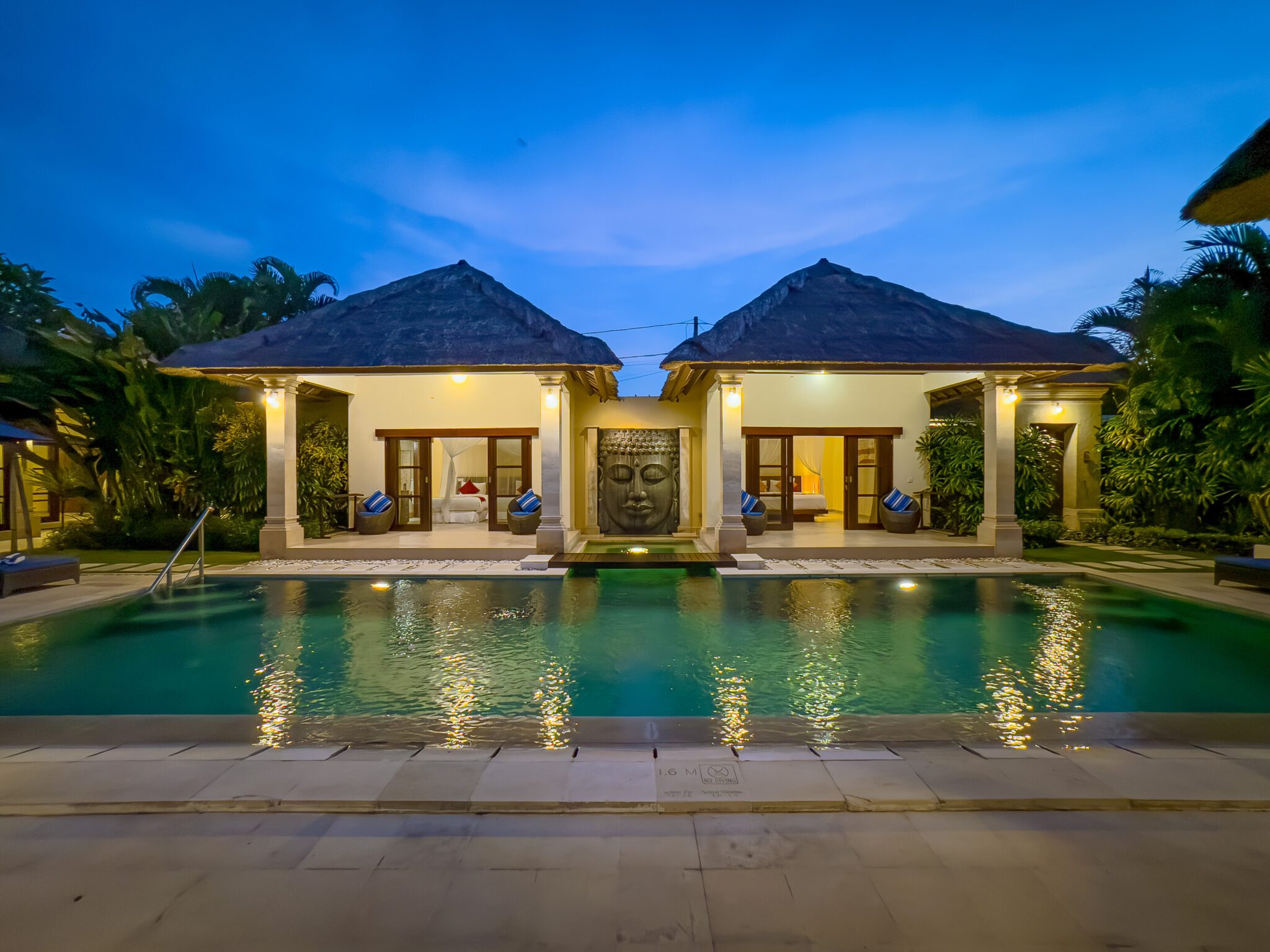 Cozy night view of the illuminated poolside patio and tropical garden at Villa Saphir Seminyak by Villa Bugis villa Seminyak.