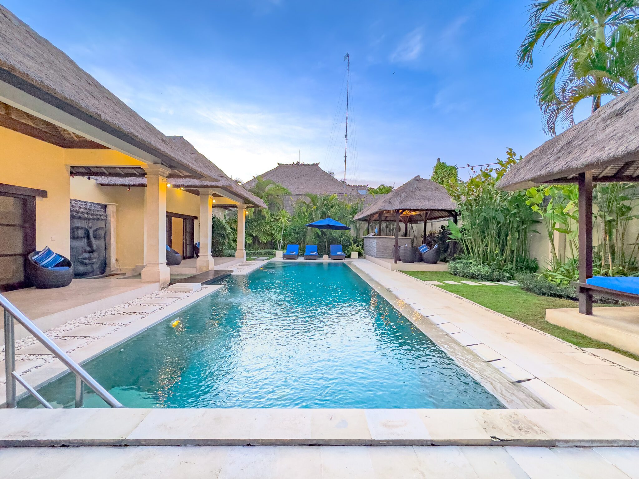 Sunlit private outdoor swimming pool surrounded by comfortable sun loungers and a lush tropical garden at Villa Saphir Seminyak by Villa Bugis, a luxury villa Seminyak.