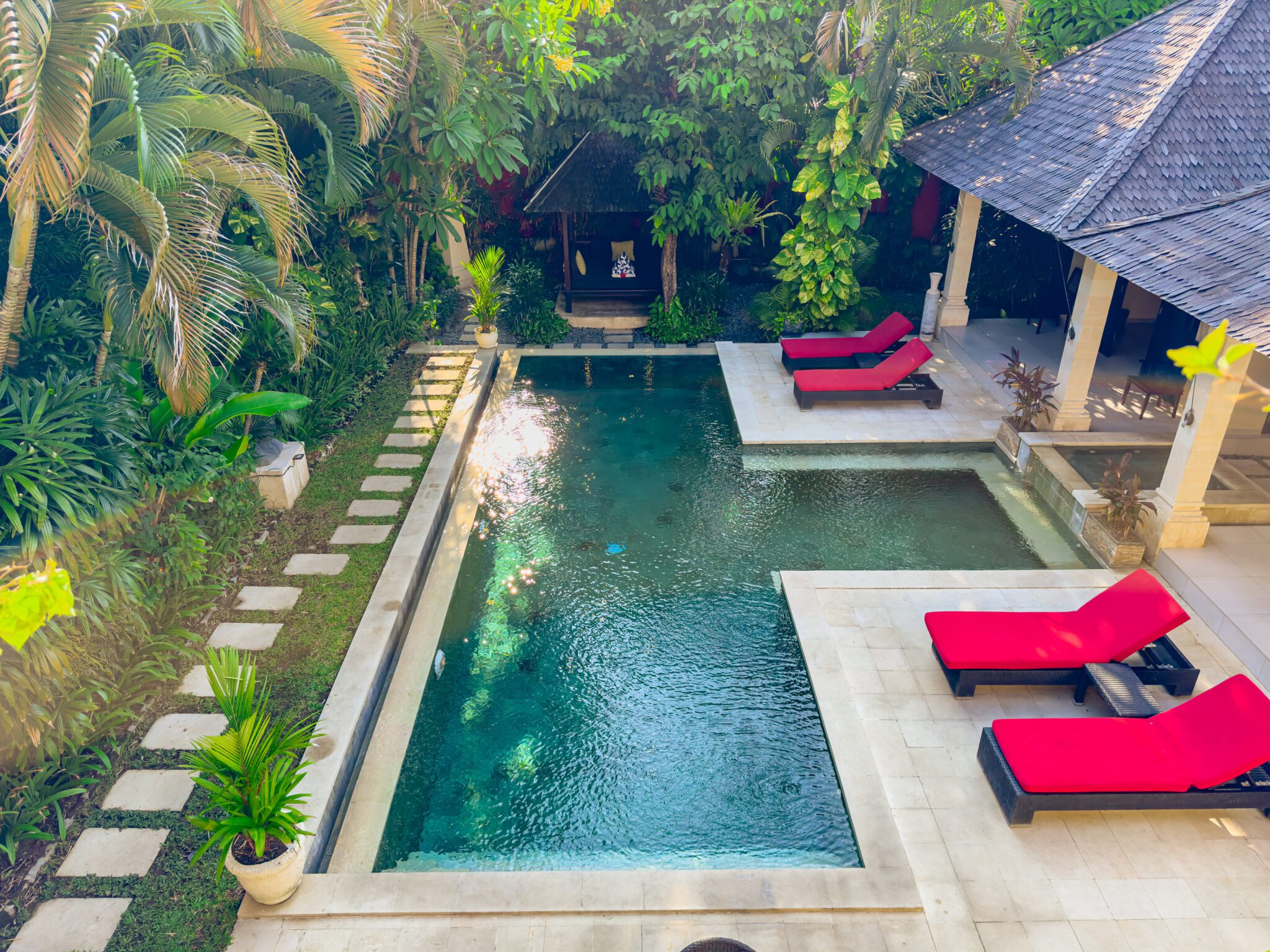 Aerial daytime perspective of the manicured garden lawn and large pool deck at Villa Tresna Seminyak by Villa Bugis Seminyak villas.