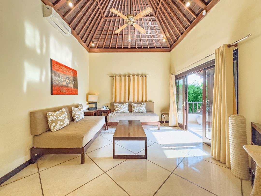 Bright upstairs TV room with sofas and sliding doors to a balcony at Villa Tresna Seminyak, Bali