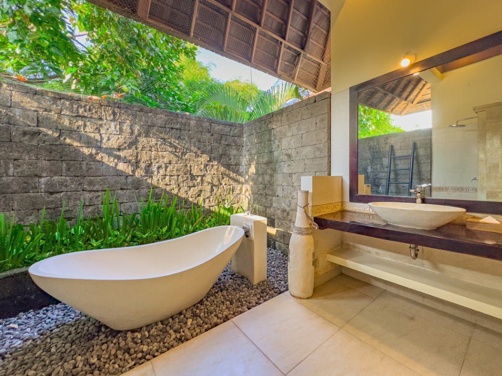 Spacious bathtub and elegant stone textures inside the master ensuite bathroom at Villa Tresna Seminyak by Villa Bugis villa Seminyak.