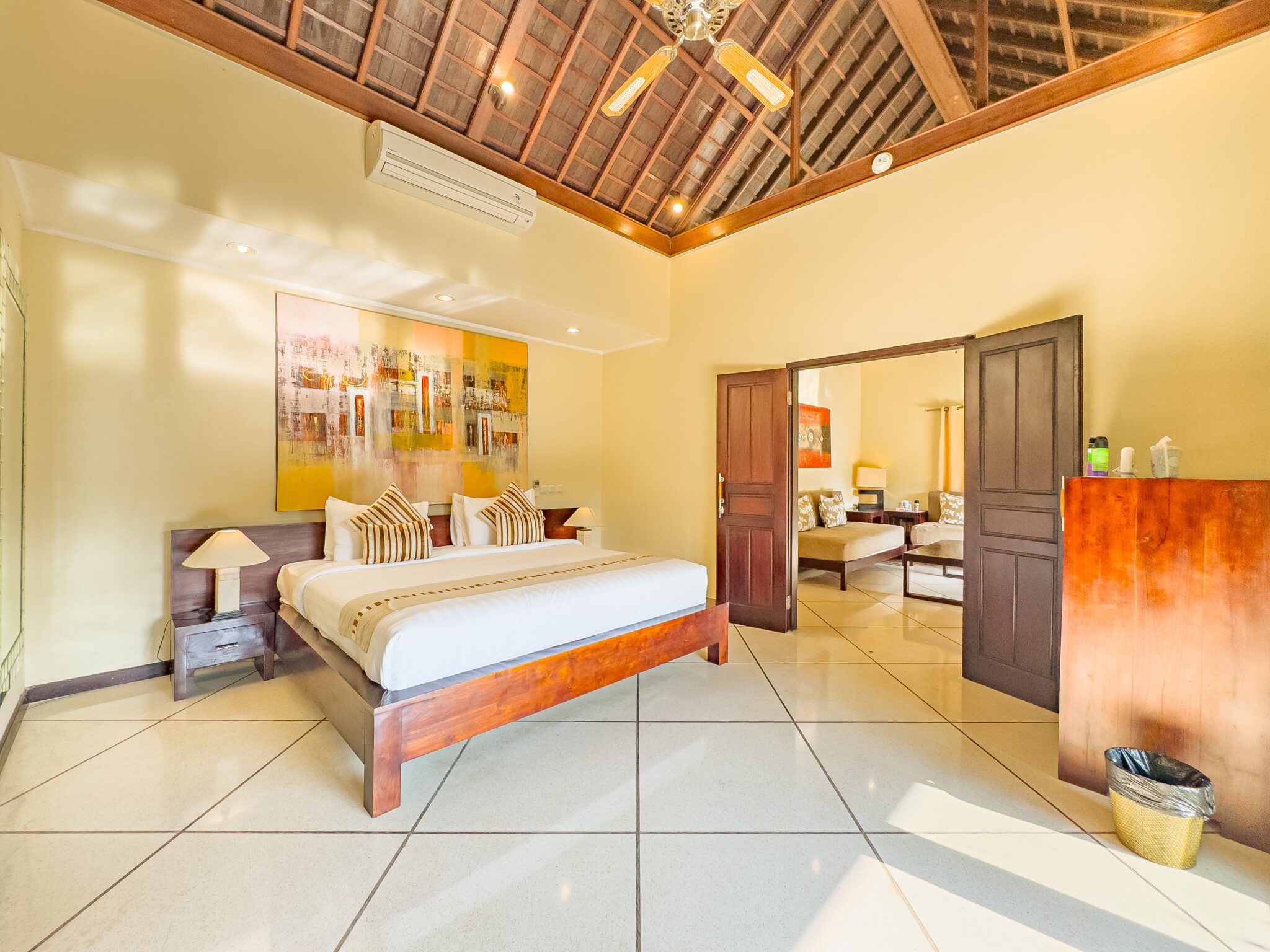 Spacious interior layout of bedroom 1 at Villa Tresna Seminyak by Villa Bugis Seminyak villas, complete with air conditioning and elegant wooden furnishings.