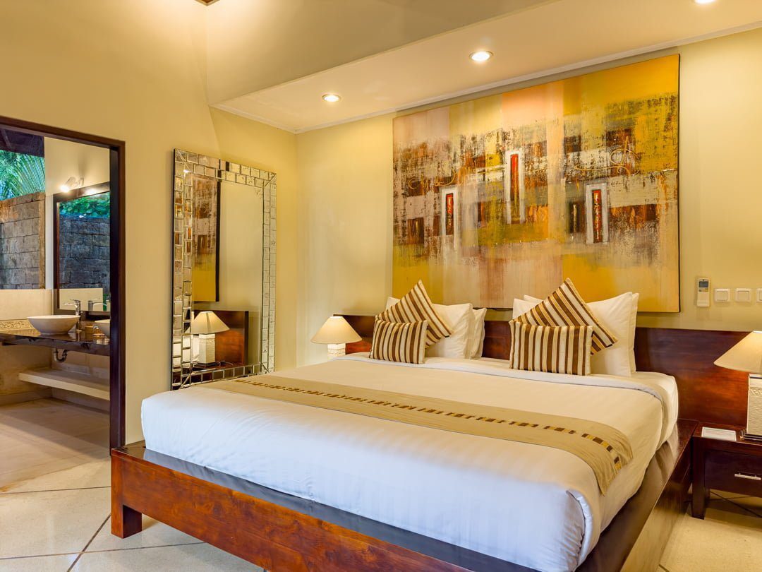 Master bedroom suite featuring a luxurious king-size bed with tropical decor at Villa Tresna Seminyak by Villa Bugis, a top-rated villa Seminyak.