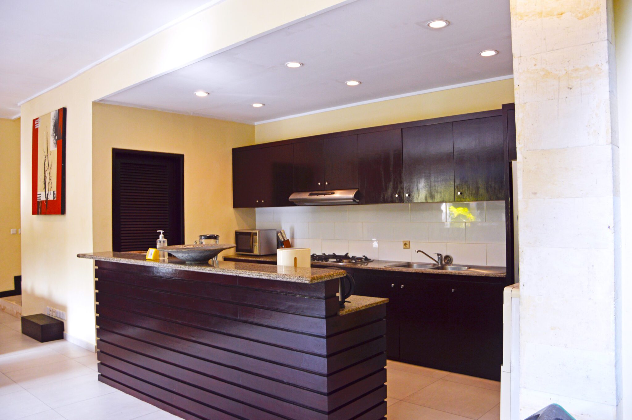 Clean fully-fitted kitchen and minimalist island bar at Villa Tresna Seminyak by Villa Bugis, offering home-style convenience in Seminyak villas.