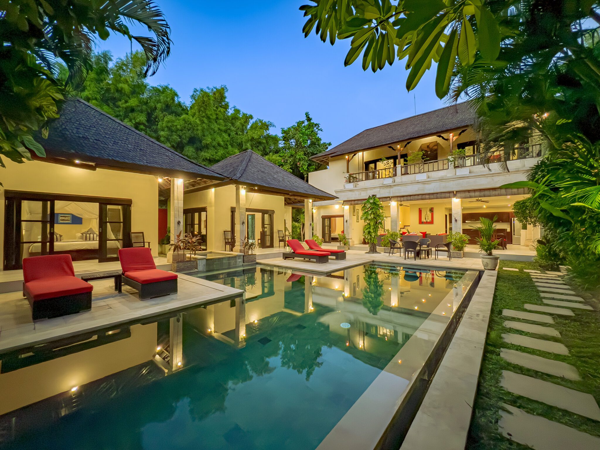 Serene evening ambiance with warm pool lighting reflecting on the water at Villa Tresna Seminyak by Villa Bugis Seminyak villas.