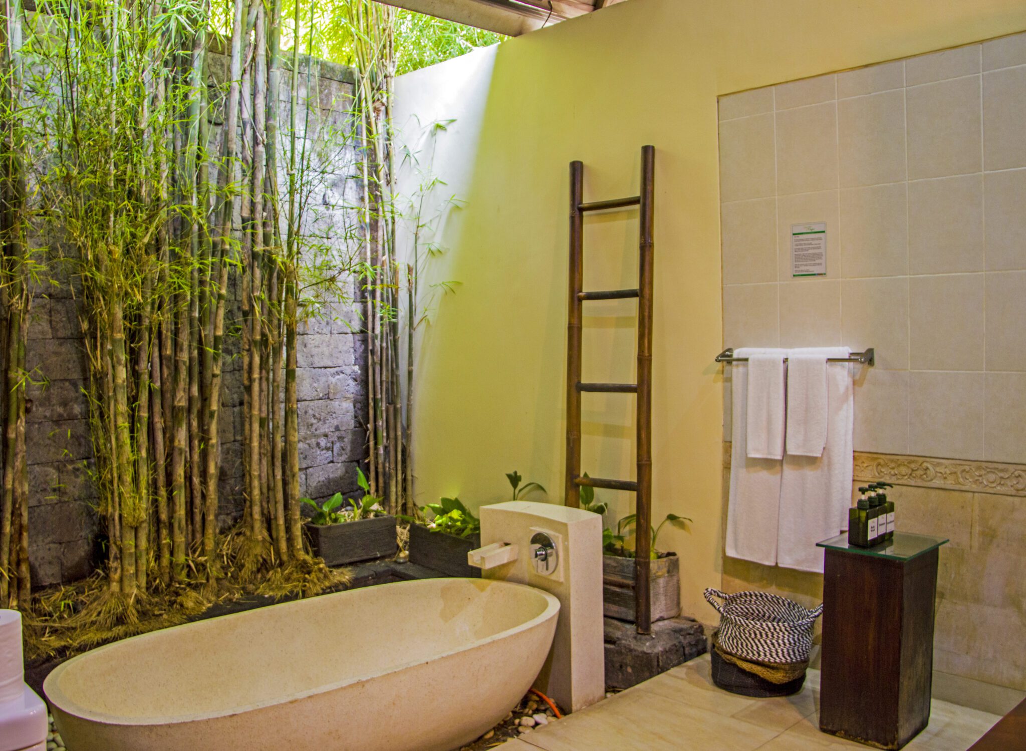 Well-lit vanity mirror, stone textures, and a soaking bathtub in the bathroom of bedroom 3 at Villa Tresna Seminyak by Villa Bugis Seminyak villas.