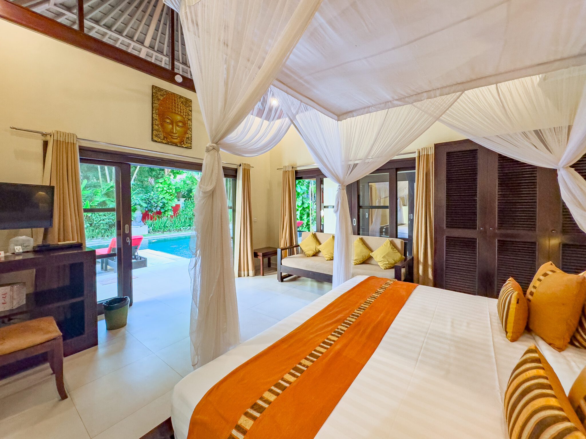 Stylish wooden bed frame and tropical accents with pool views in bedroom 3 at Villa Tresna Seminyak by Villa Bugis villa Seminyak.