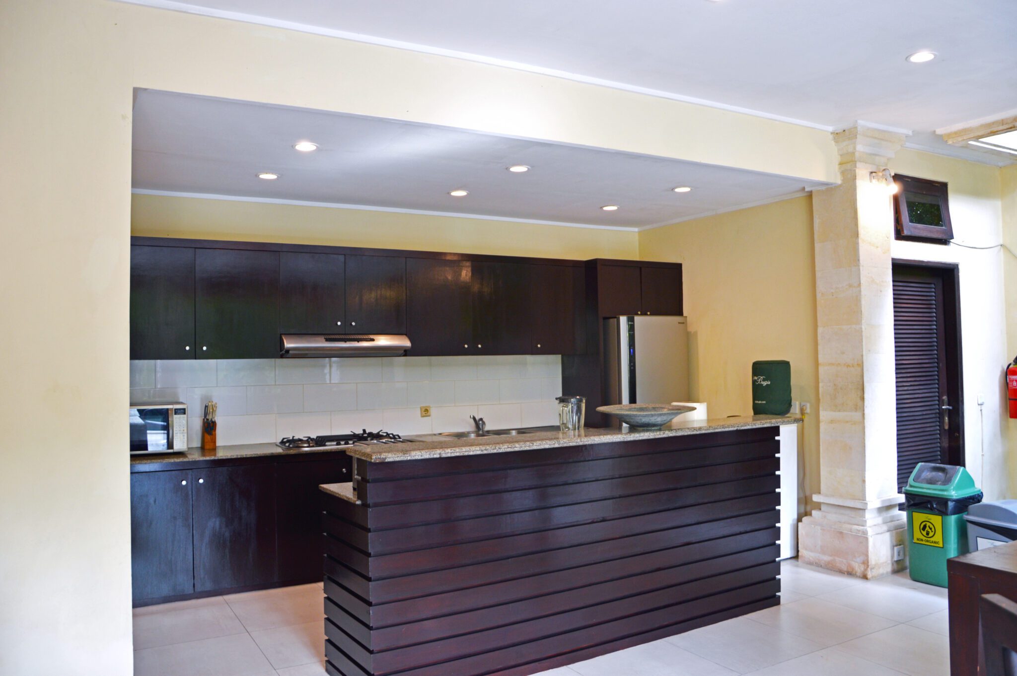 Western-standard kitchen setup with sleek wooden cabinets at Villa Tresna Seminyak by Villa Bugis, a luxury feature for a villa Seminyak stay.
