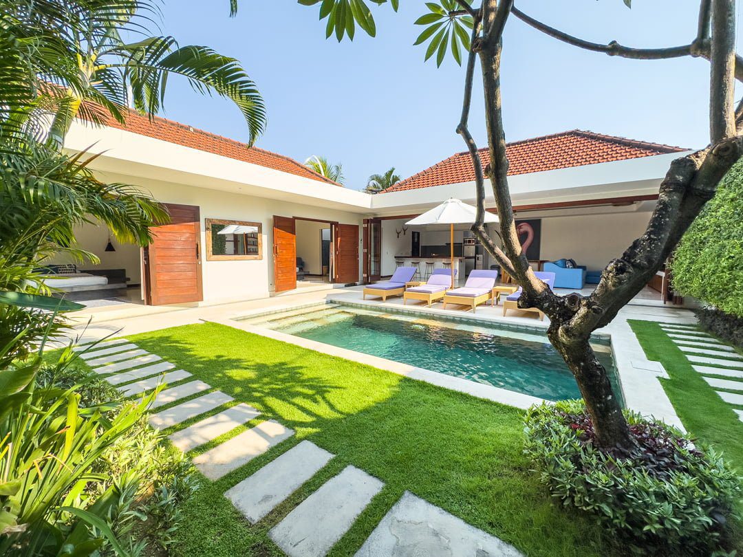 Sunny daytime perspective of the manicured garden lawn and private pool deck at Villa Umah Kupu-Kupu 2 Seminyak by Villa Bugis Seminyak villas.