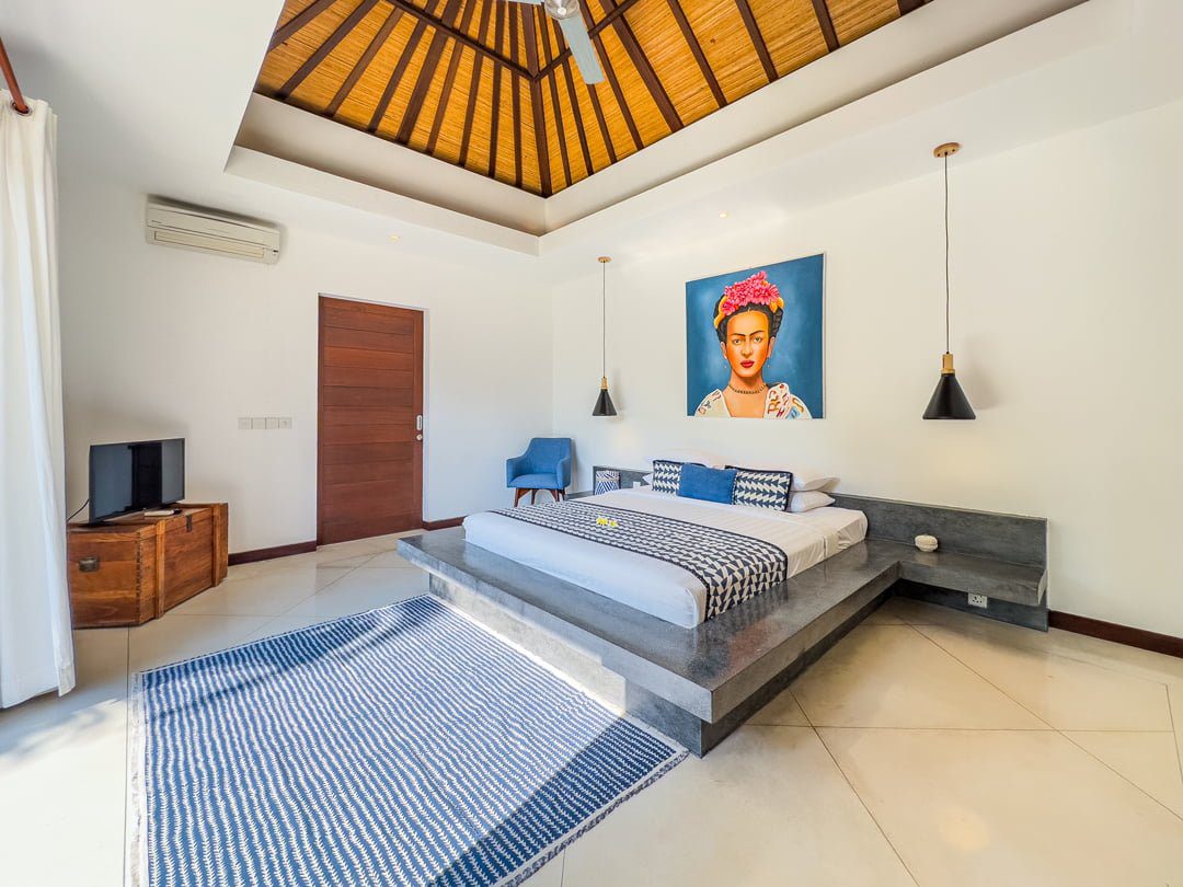 Spacious interior layout of bedroom 1 at Villa Umah Kupu-Kupu 2 Seminyak by Villa Bugis Seminyak villas, complete with air conditioning and elegant wooden furnishings.