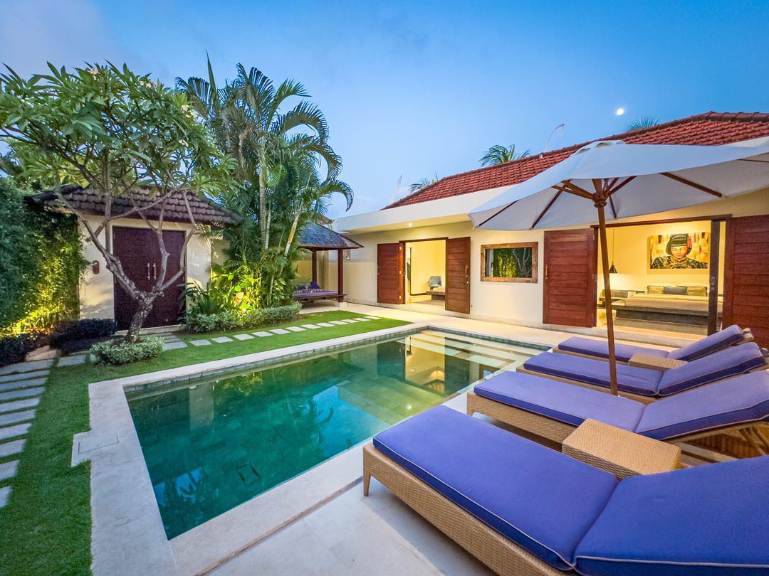 Serene evening ambiance with warm pool lighting reflecting on the water at Villa Umah Kupu-Kupu 2 Seminyak by Villa Bugis Seminyak villas.