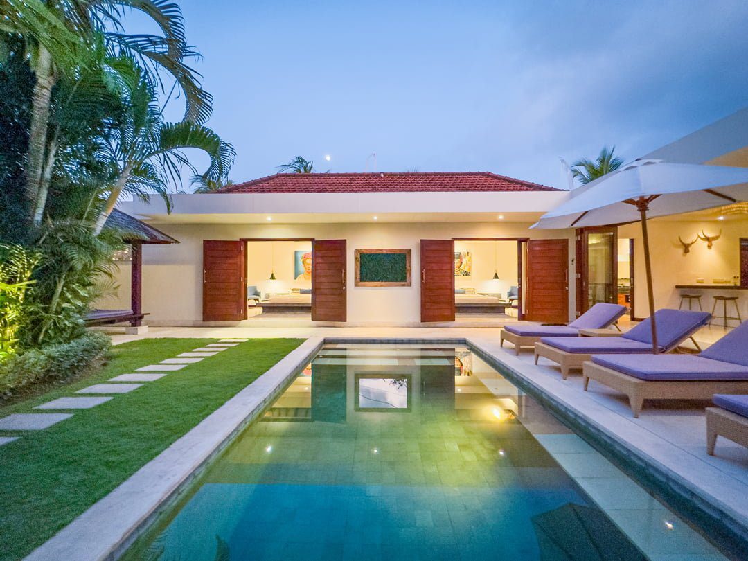 Cozy night view of the illuminated poolside patio and tropical garden at Villa Umah Kupu-Kupu 2 Seminyak by Villa Bugis villa Seminyak.