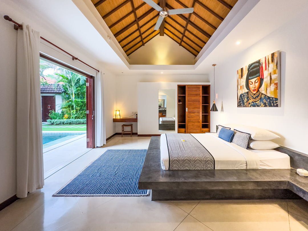Cozy second bedroom with comfortable bedding, warm lighting, and pool views at Villa Umah Kupu-Kupu 2 Seminyak by Villa Bugis, ideal for Seminyak villas guests.