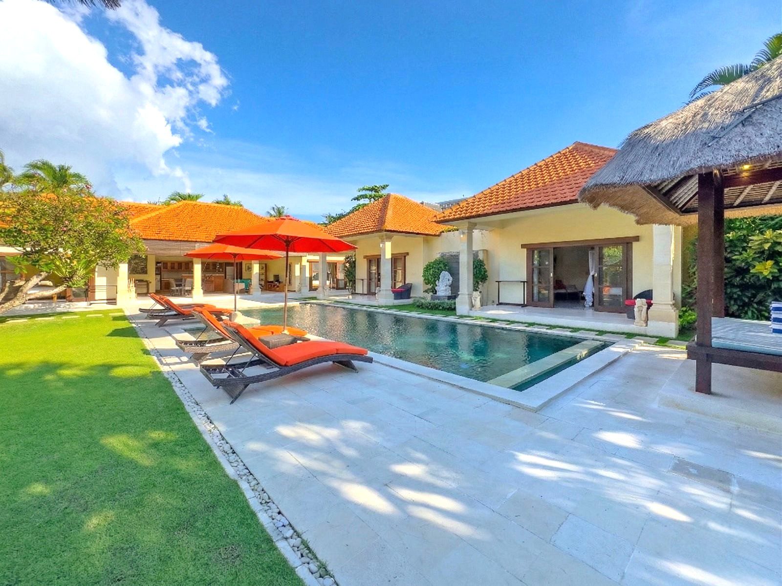 Tropical oasis landscape and spacious poolside relaxation terrace at Villa Vara Seminyak by Villa Bugis, ideal for family vacations in a villa Seminyak.