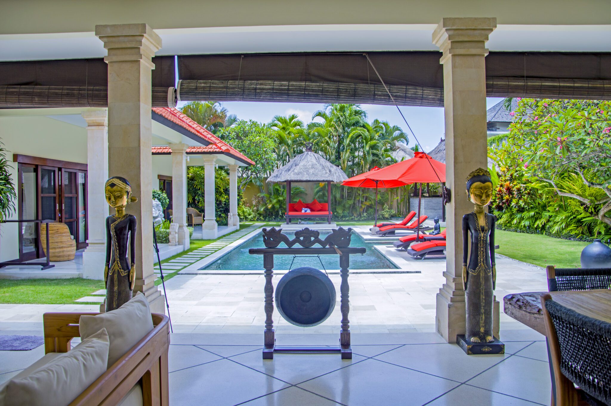 Open-air living room pavilion with plush sofa seating facing the private pool at Villa Vara Seminyak by Villa Bugis villa Seminyak.