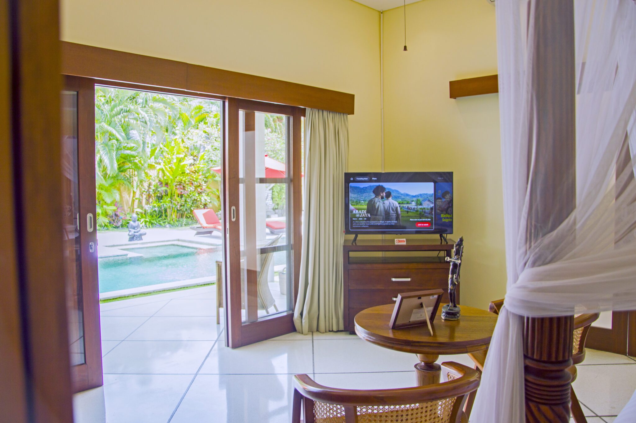 High ceilings, cozy lounge seating, and premium bedding with pool views in bedroom 1 at Villa Vara Seminyak by Villa Bugis villa Seminyak.