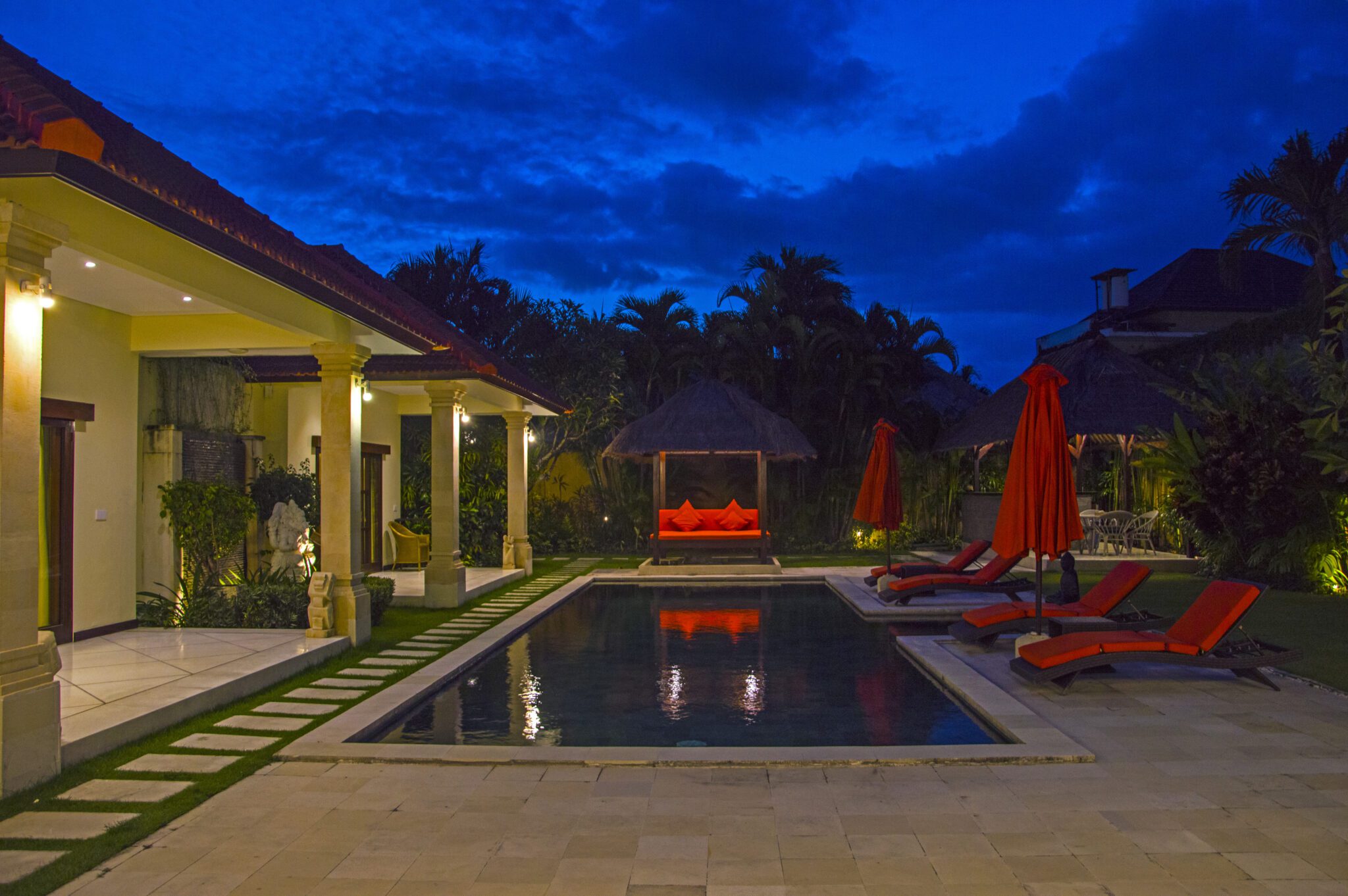 Serene evening ambiance with warm pool lighting reflecting on the water at Villa Vara Seminyak by Villa Bugis Seminyak villas.
